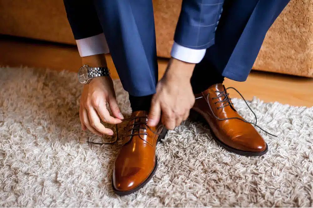 homme laçant ses chaussures marrons